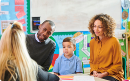 A family and child sitting down with a childcare provider at a childcare center.