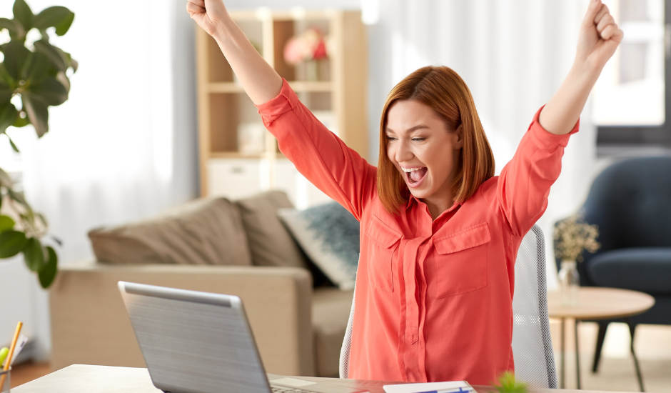 woman cheering near laptop: excited about capturing new leads