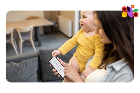 Mom holding baby while sending a text: how to start a daycare business plan